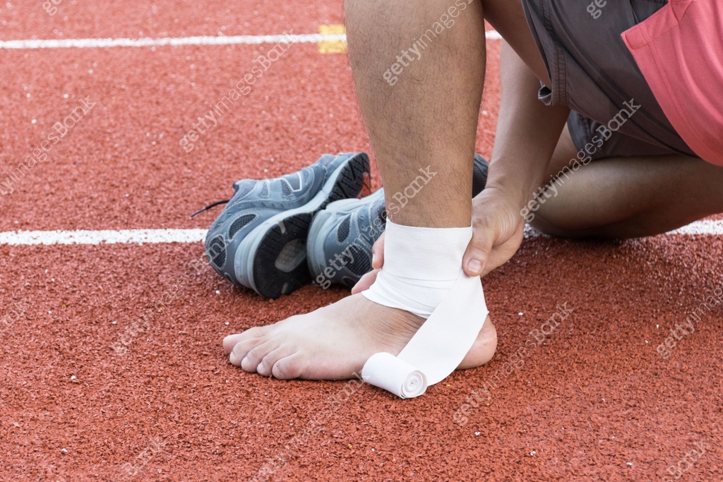 man applying compression bandage onto ankle injury After exercise ...
