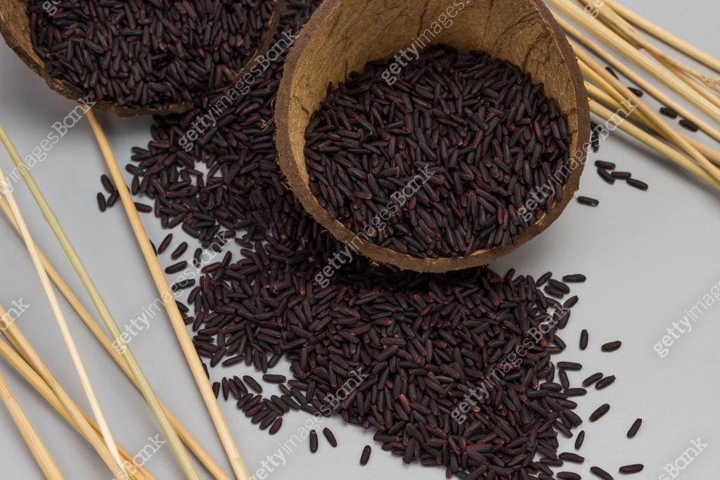 Black rice in coconut shell. Rice grains are scattered on gray 이미지 ...