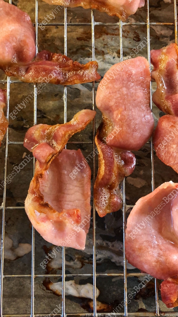 Image of crispy, greasy bacon rashers on grill tray, fat rind cooking ...