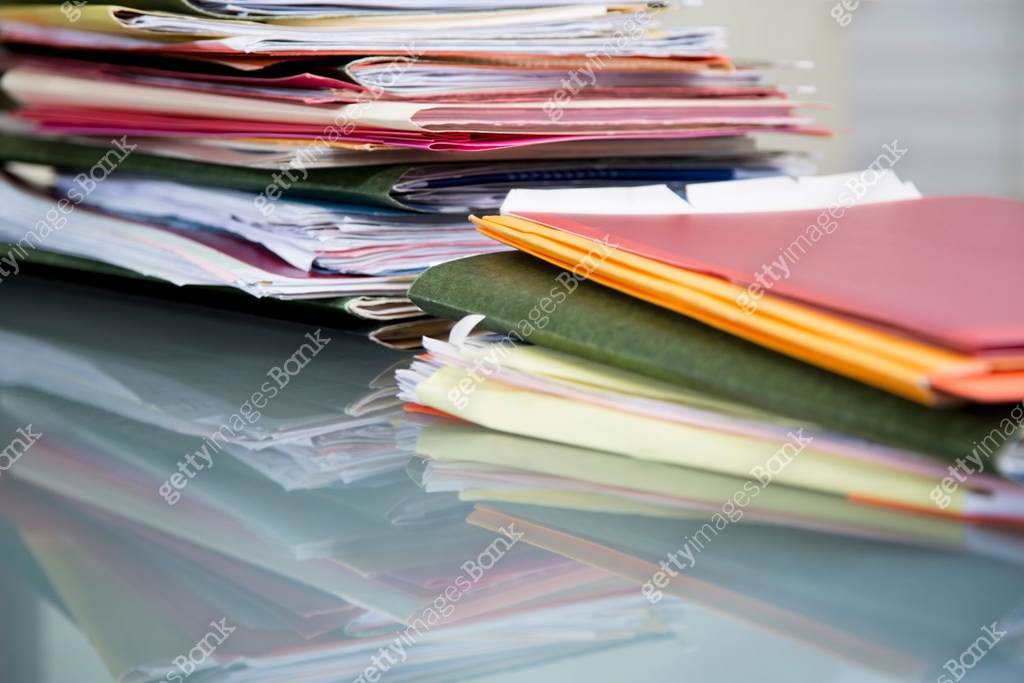Stack of file folders with documents on a glass top desk. 이미지 ...