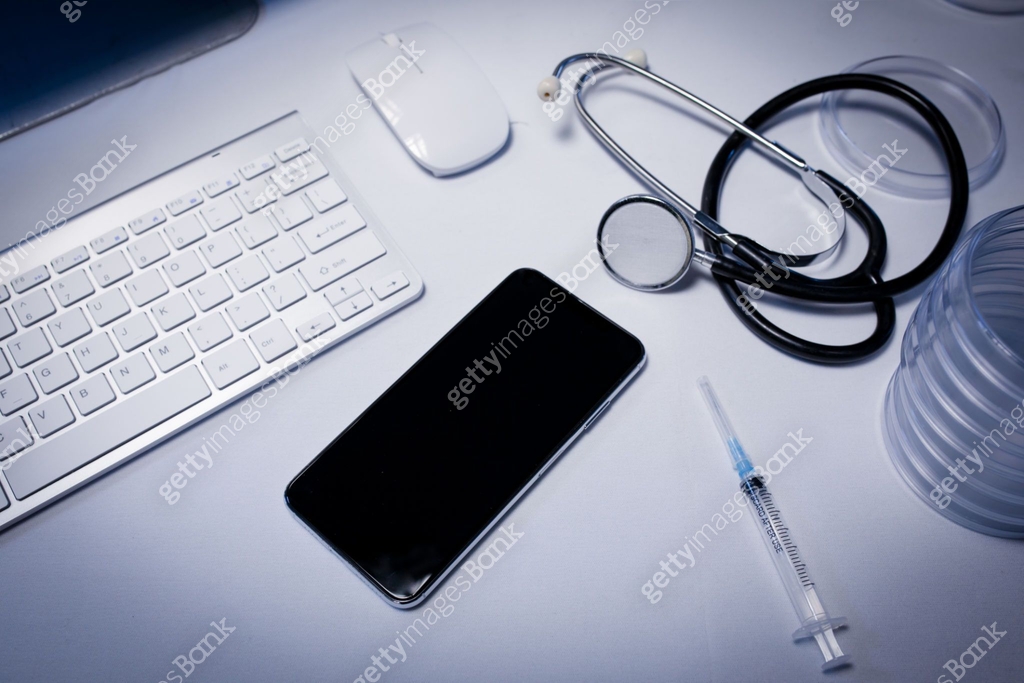 Desk in doctors surgery with smartphone computer keyboard syringe and ...
