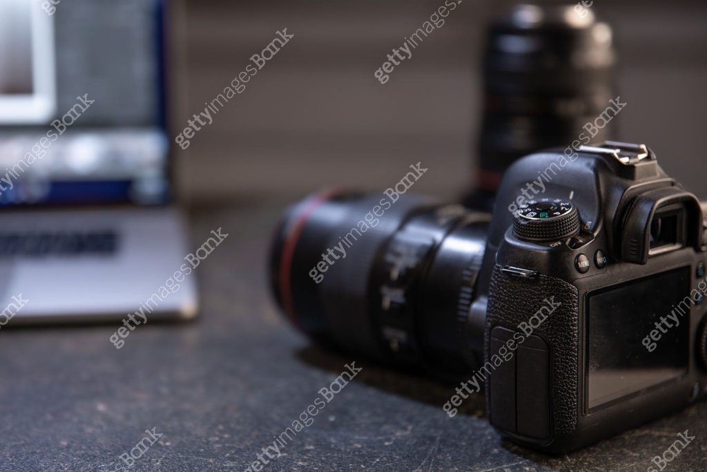 Digital professional camera on the table near the laptop close up. 이미지 ...