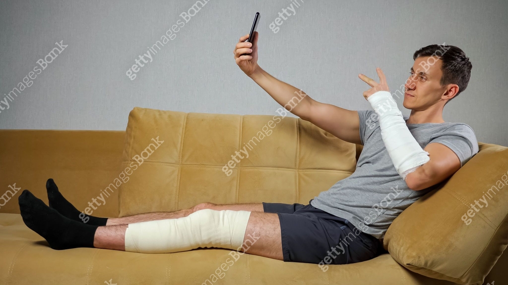 Young Man With Injured Knee And Forearm Takes Selfies 1357523587 Young Man With Injured Knee And Forearm Takes Selfies 1357523587