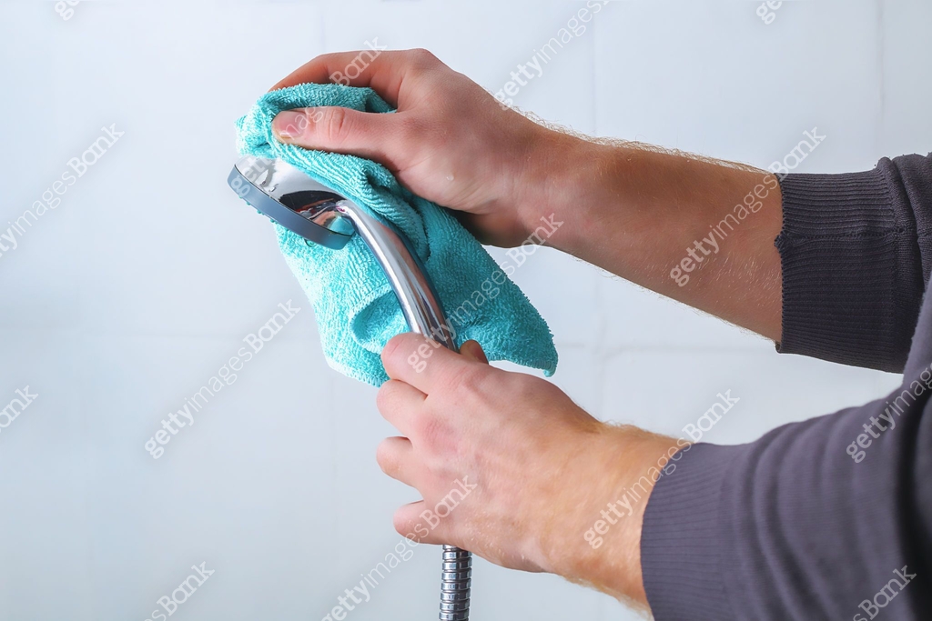 A man wipes a shower head with rag. Cleaning of the house, bathroom ...