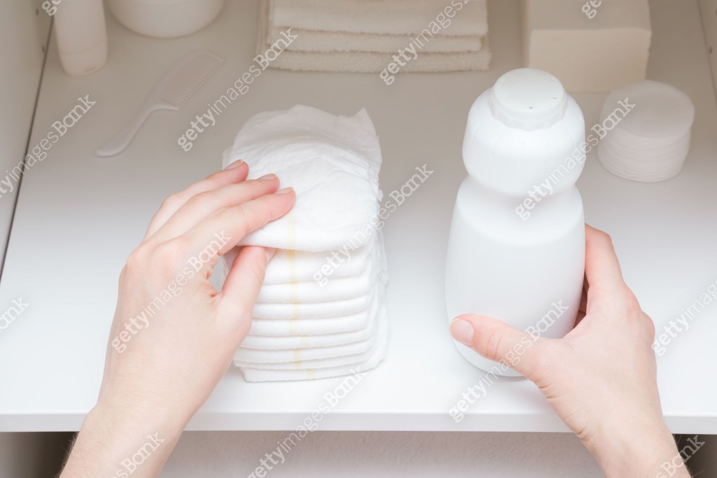 Young adult mother hands taking white bottle of talcum powder and new ...