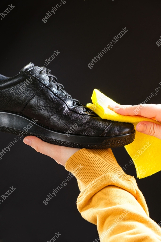 A man wipes leather men's black shoes with a yellow shoe rag. 이미지 ...