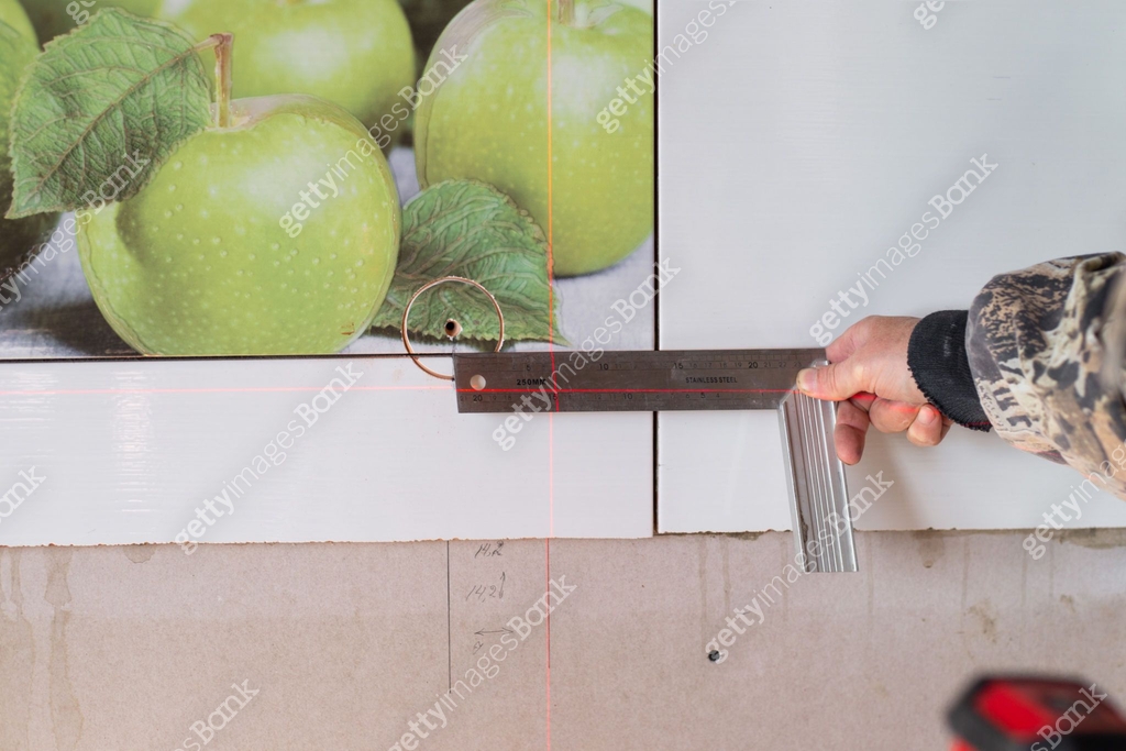 A man using a laser level and a ruler makes markings for the opening of ...