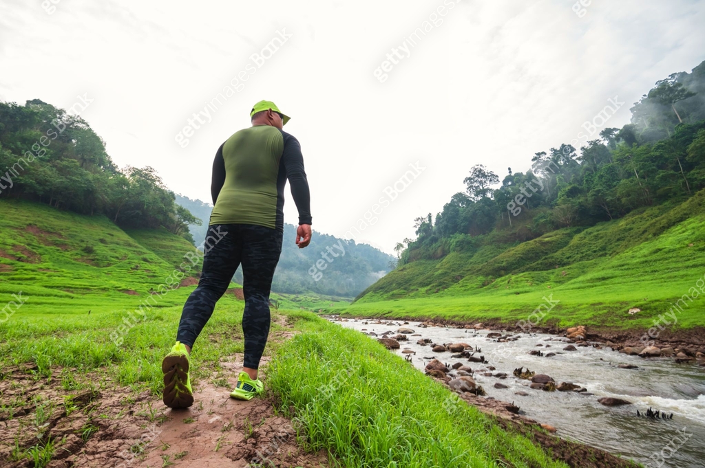 Young Asian men running in nature trails, among forests, valleys and ...