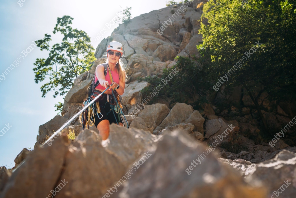 Smiling athletic woman in protective helmet and climbing harness ...