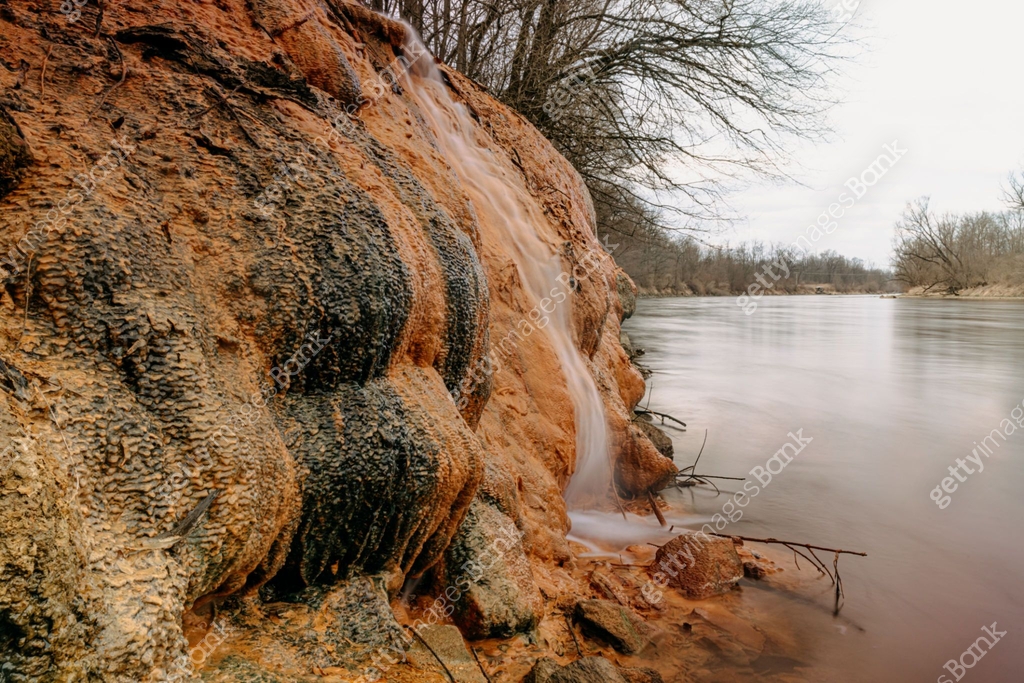 Close-up of water flowing from wet muddy rocks by river at famous ...