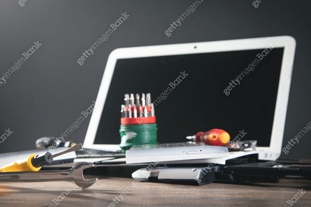 Broken laptop with a wrench and screwdriver on the table. Computer ...
