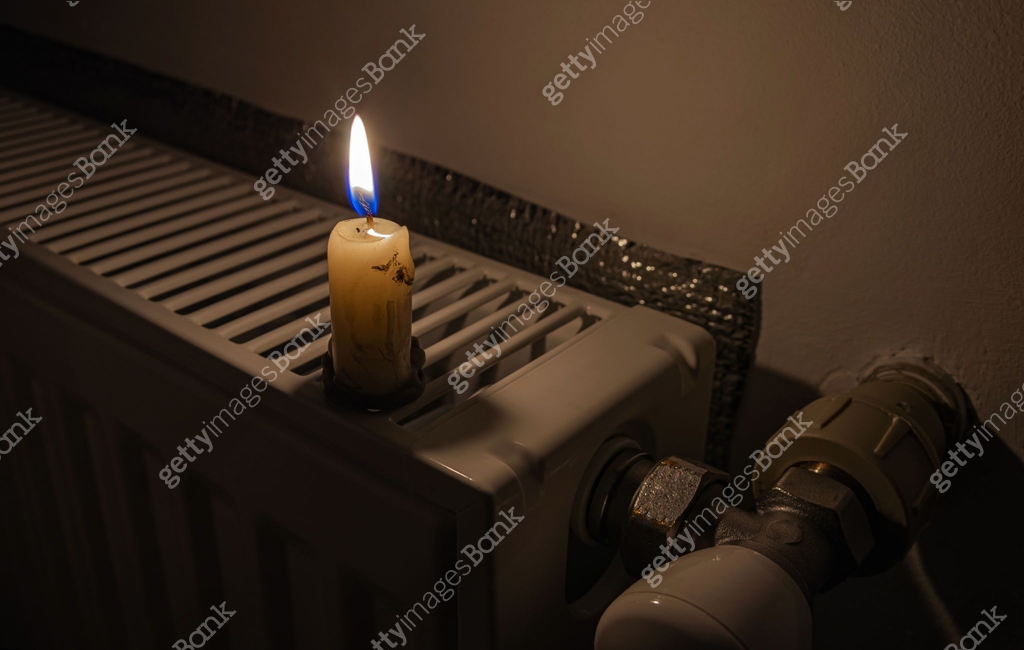 Burning candle on the radiator heating in darkness. Shutdown of heating ...