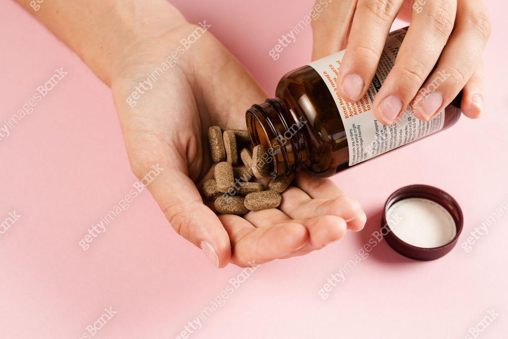 Tablets of dietary supplements in hand for daily pills intake on pink ...