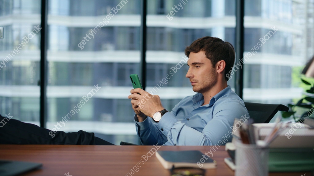 Serious boss working smartphone in panoramic place. Employee texting ...