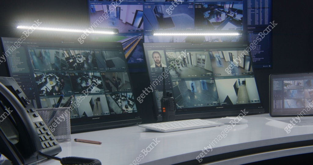 Computer monitors and tablet showing video footage of surveillance ...