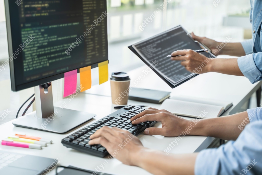 programmer writing program code with two monitors and working on a new ...