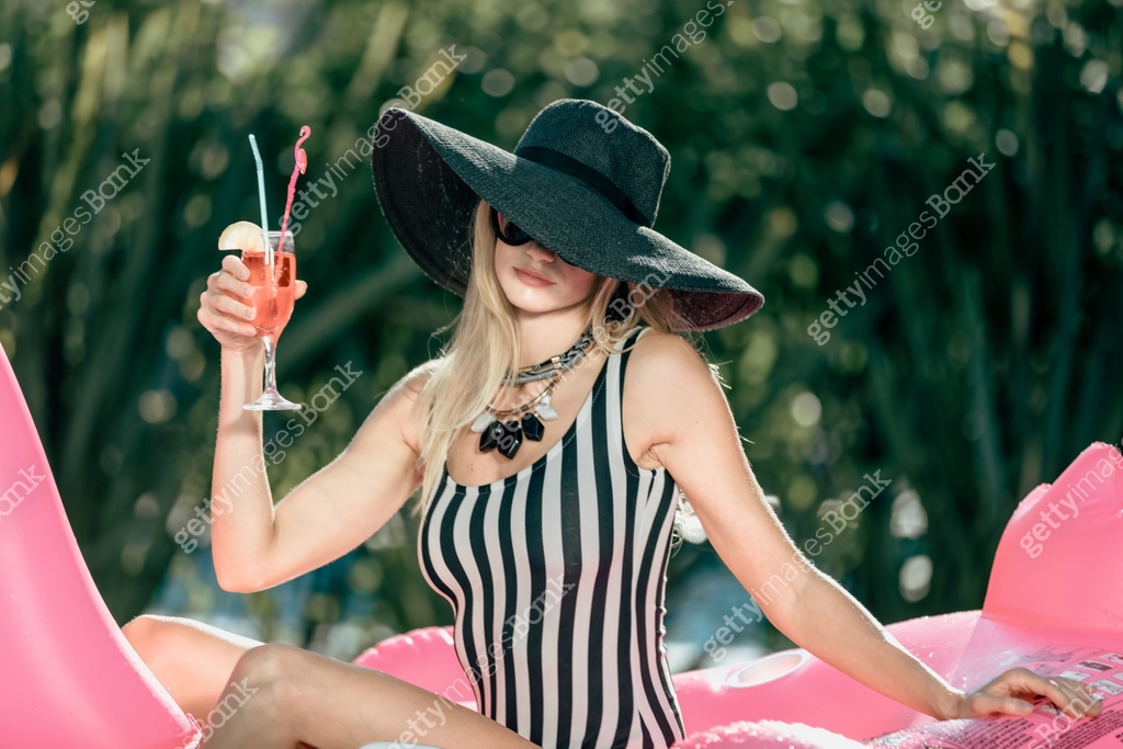 Beauty young woman sunbathing and refreshing in the pool on the pink ...