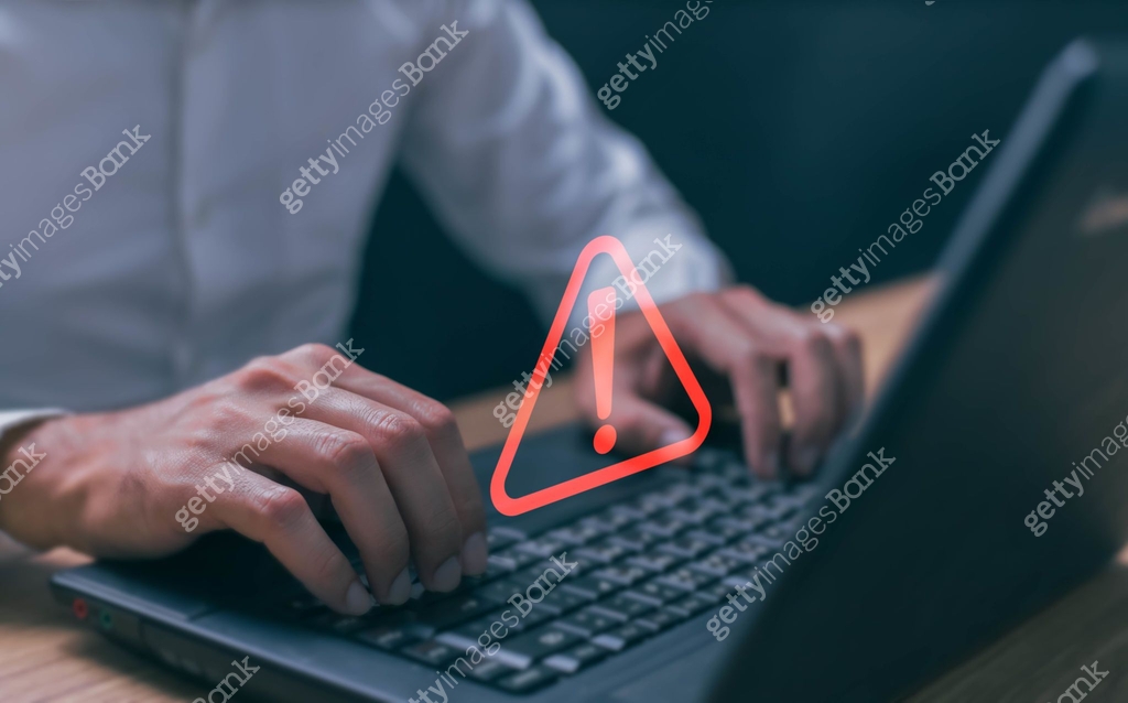 Businessman using computer laptop with triangle caution warning sing ...