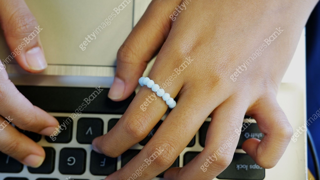 Female hands are typing on a laptop keyboard with a ring bead on the ...