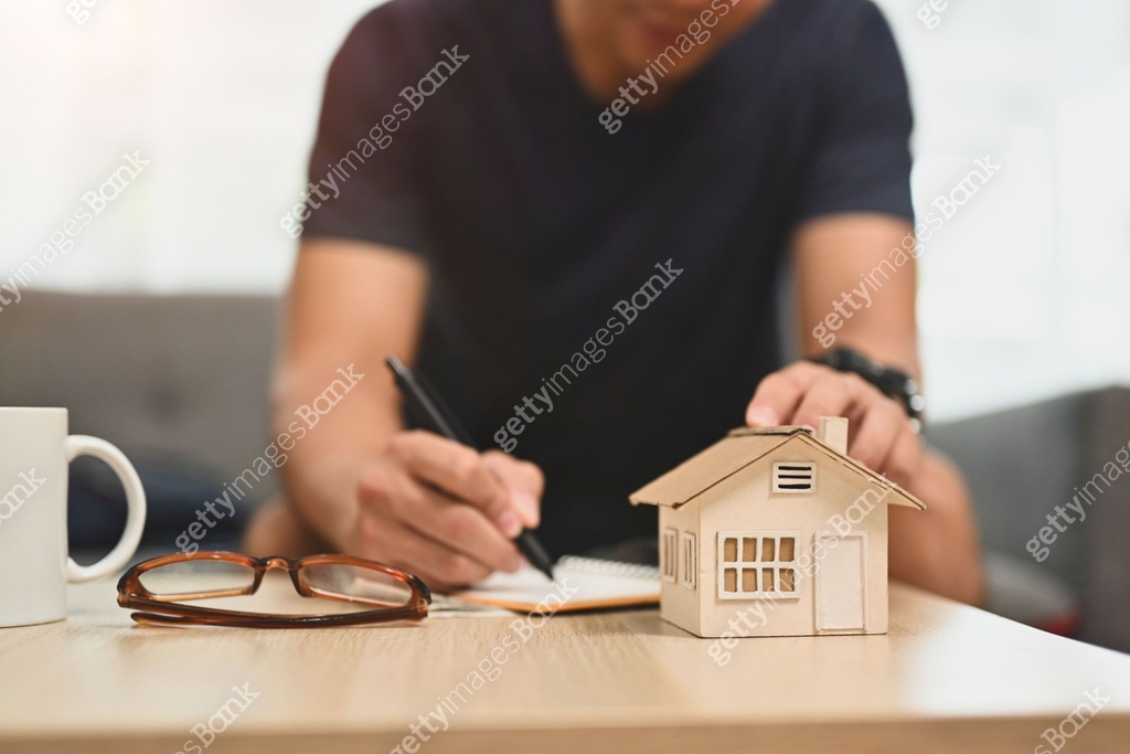 Man hand touching house model and writing notes.planning and ...