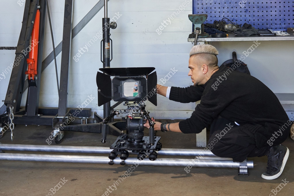 a videographer adjusts a professional movie camera standing on a camera ...