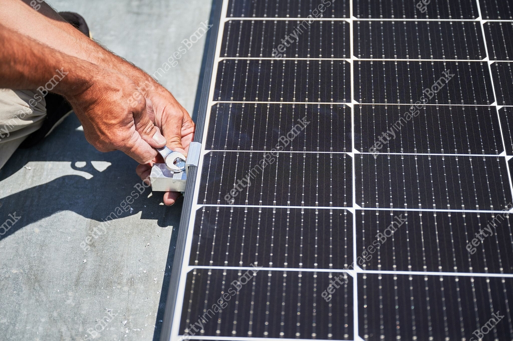 Worker building photovoltaic solar panel system on rooftop of house ...