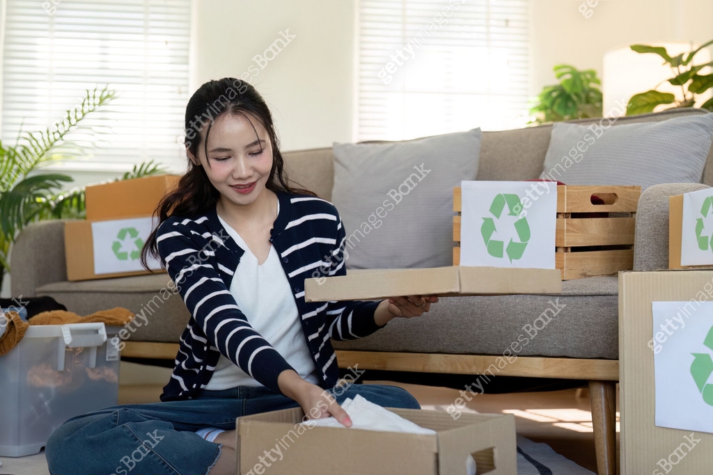 Woman pack box with used clothes for reuse. Reusing, recycling material ...