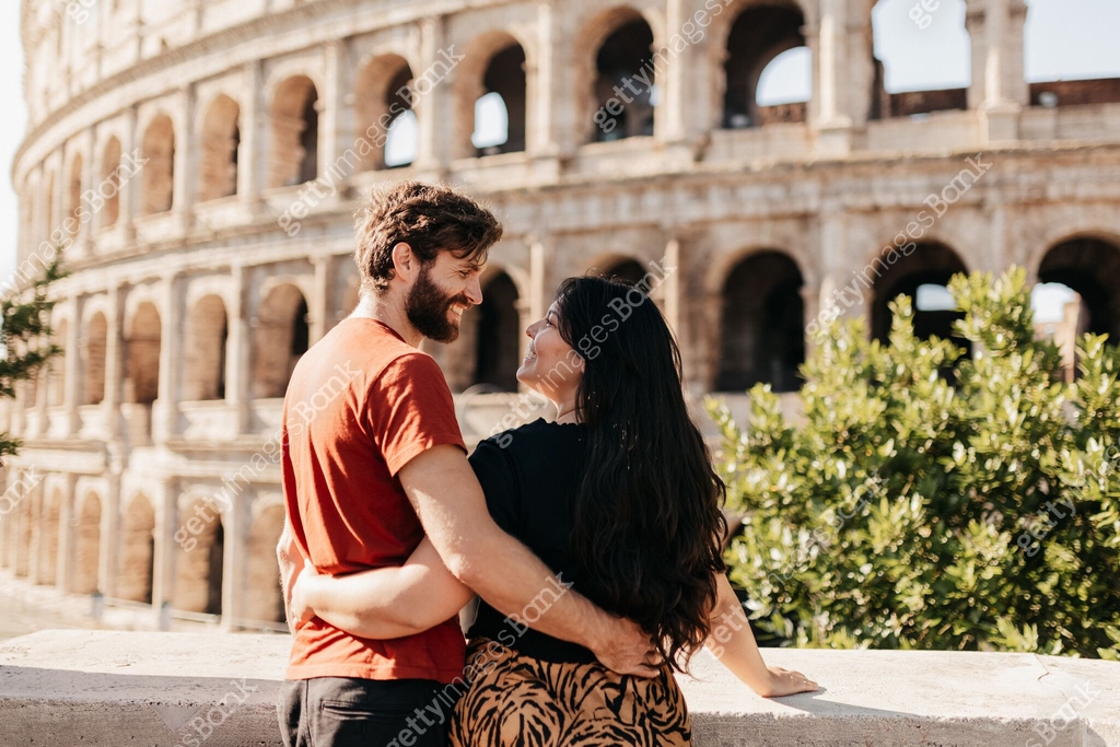 Happy couple embracing and smiling lovingly at each other by stone wall ...