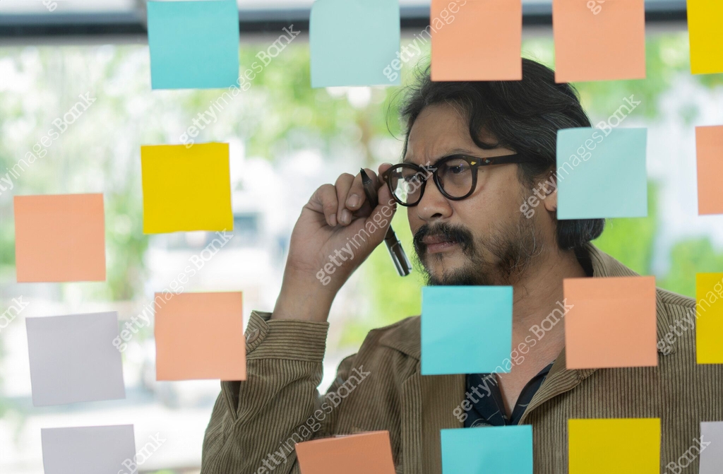 Serious thoughtful businessman ceo near glass board with adhesive ...
