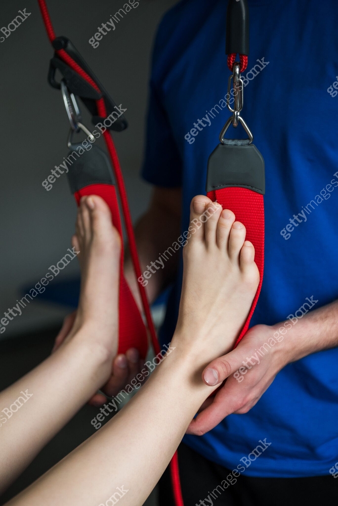 Girl legs is on red cord therapy to activate small muscles by relaxing ...