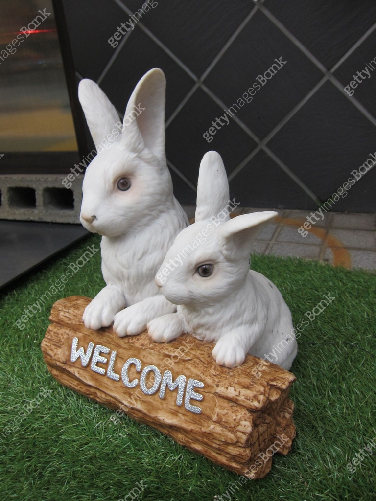 Decorative welcome sign with two white rabbit figurines on artificial ...
