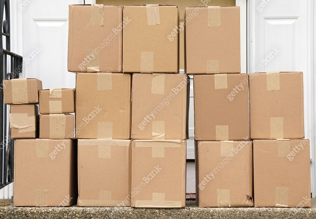 stacking delivered package boxes in front of the front door of house ...