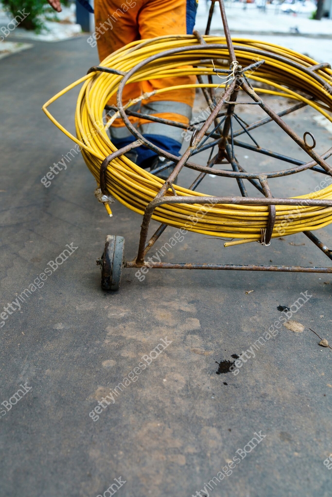 worker operating a cable pulling device used for tightening cables and ...