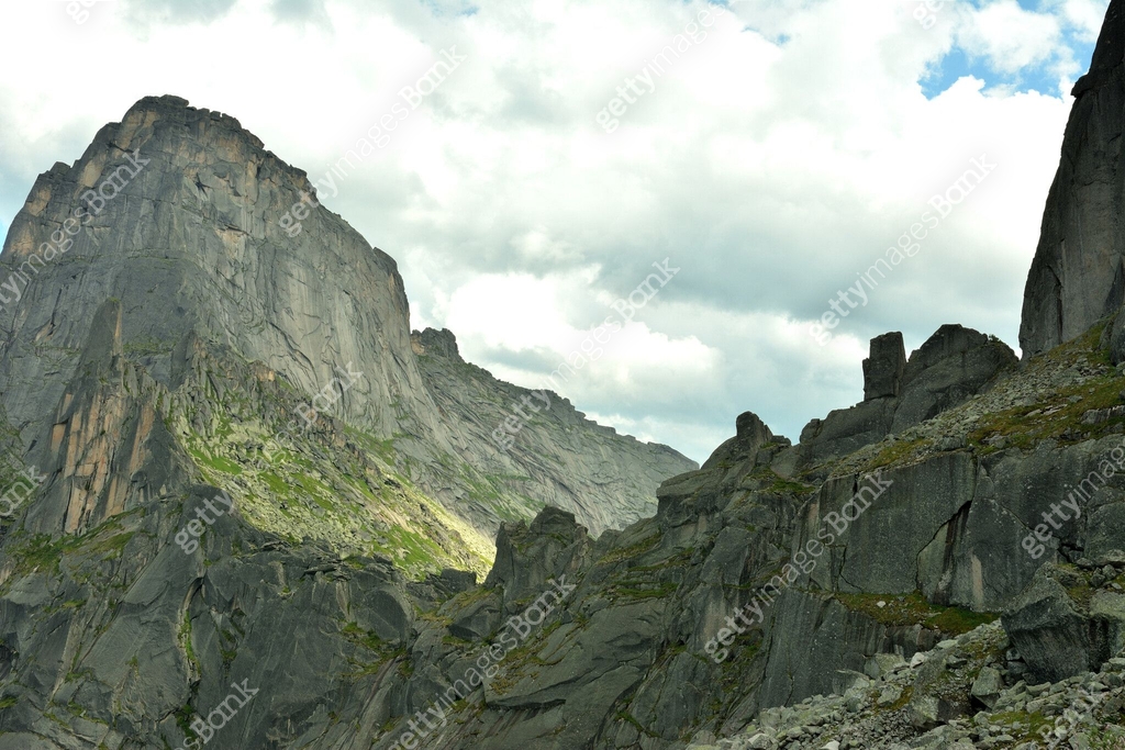 A pointed rocky ridge of a high cliff with sheer slopes connects two ...