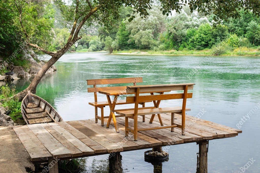 A serene lakefront with a picnic table, surrounded by trees, and a small boat dock