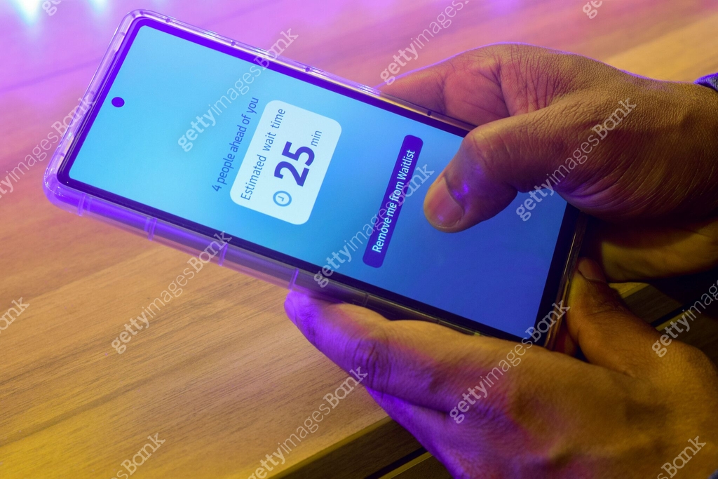 Man hand checking his mobile phone displaying estimated wait time ...