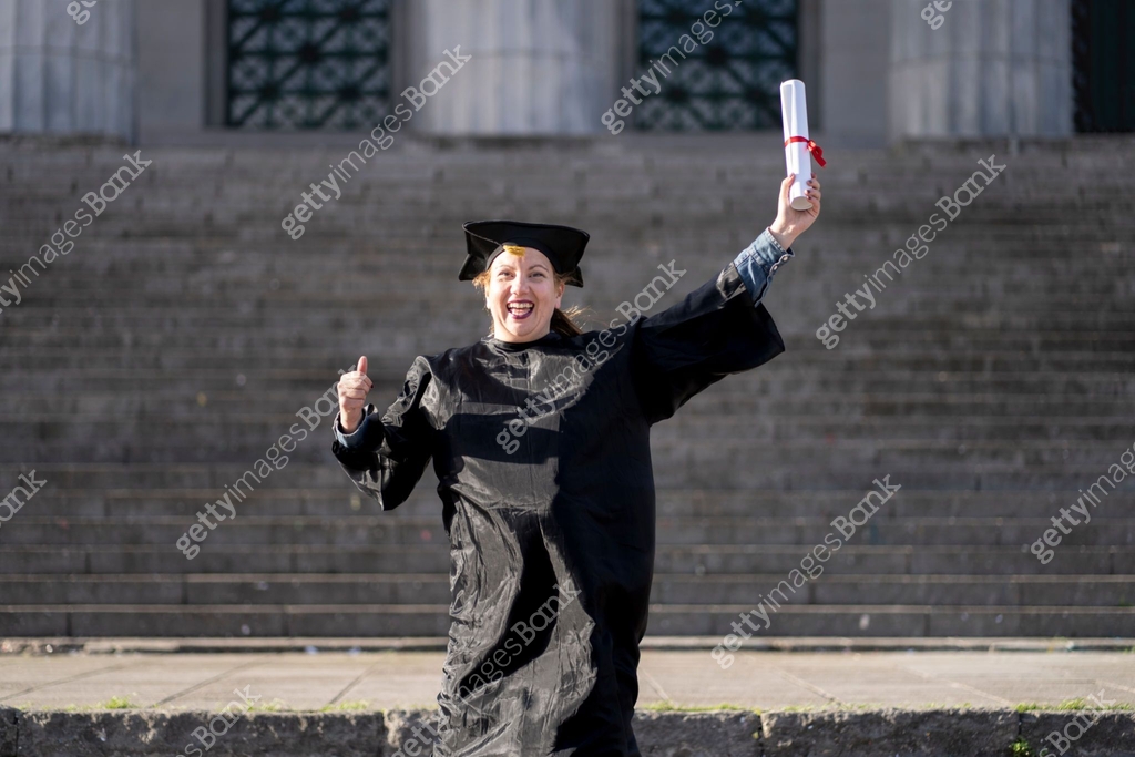 Woman recently graduated, dressed in cap and gown, with her degree in ...