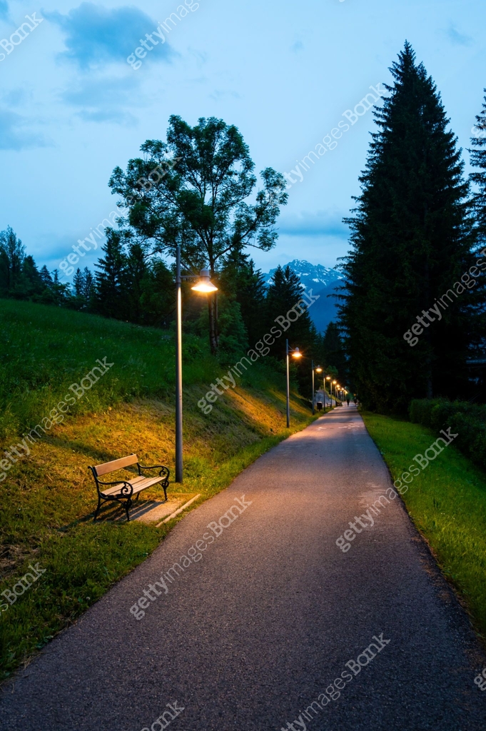 A nighttime view of a sidewalk and cycling path illuminated by street ...