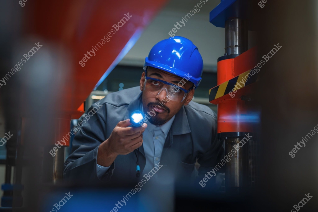 Man Checking Machine Engineering technology professional holding a flashlight and checking ...