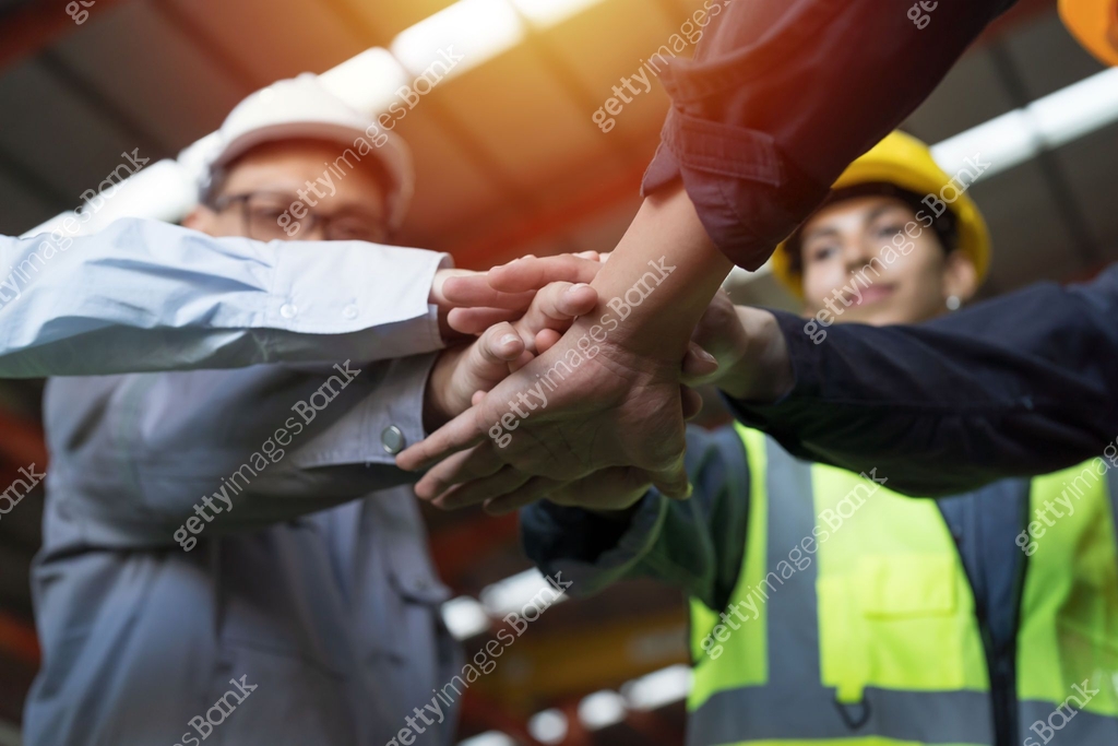 Group of male and female factory workers standing putting their hands ...