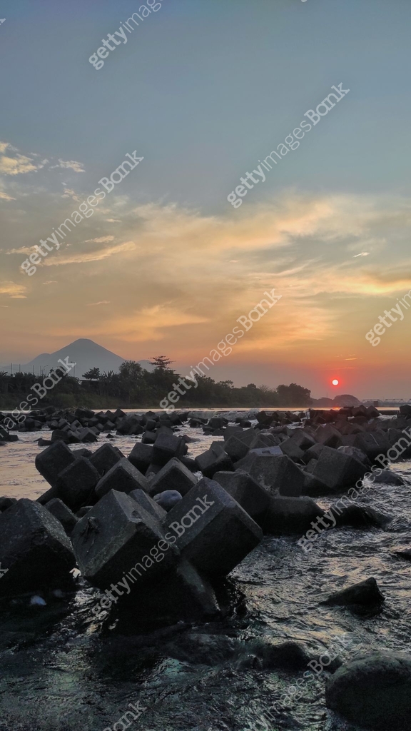 A calm river flows over large, angular rocks, creating a textured ...