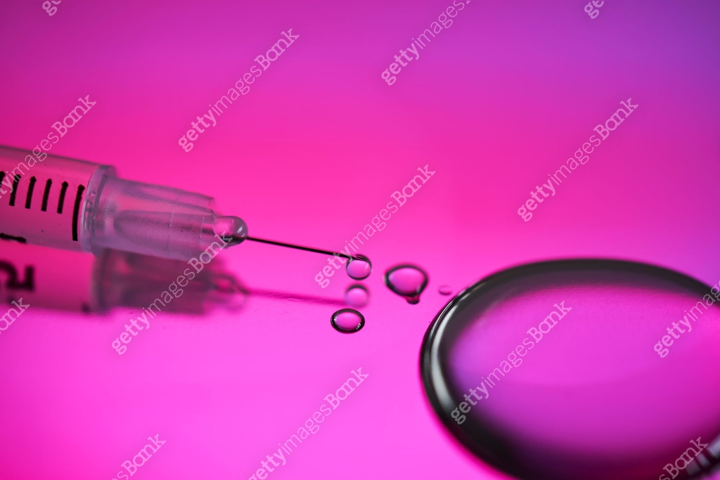 Injection syringe with a drop of drug on a rich pink background. 이미지 ...