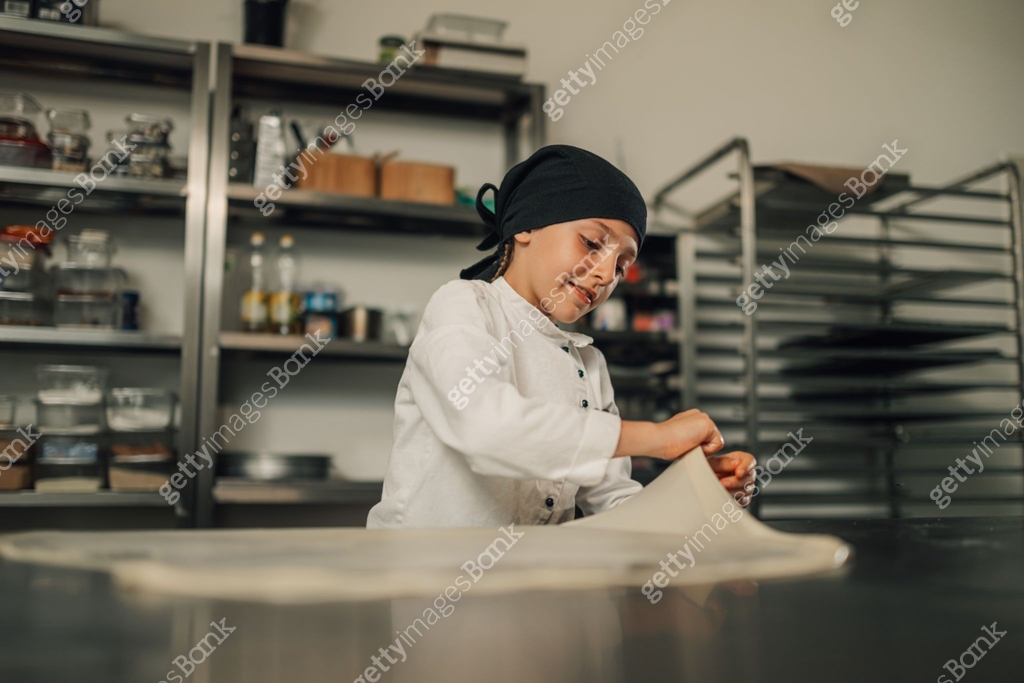 Chef Stretch Young girl chef stretching dough on counter amid kitchen equipment 이미지 ...