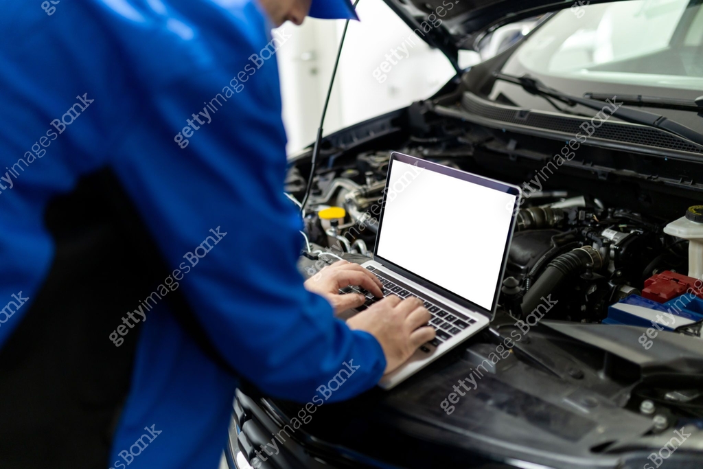 Mechanic using blank screen laptop to diagnose car issues in an auto ...
